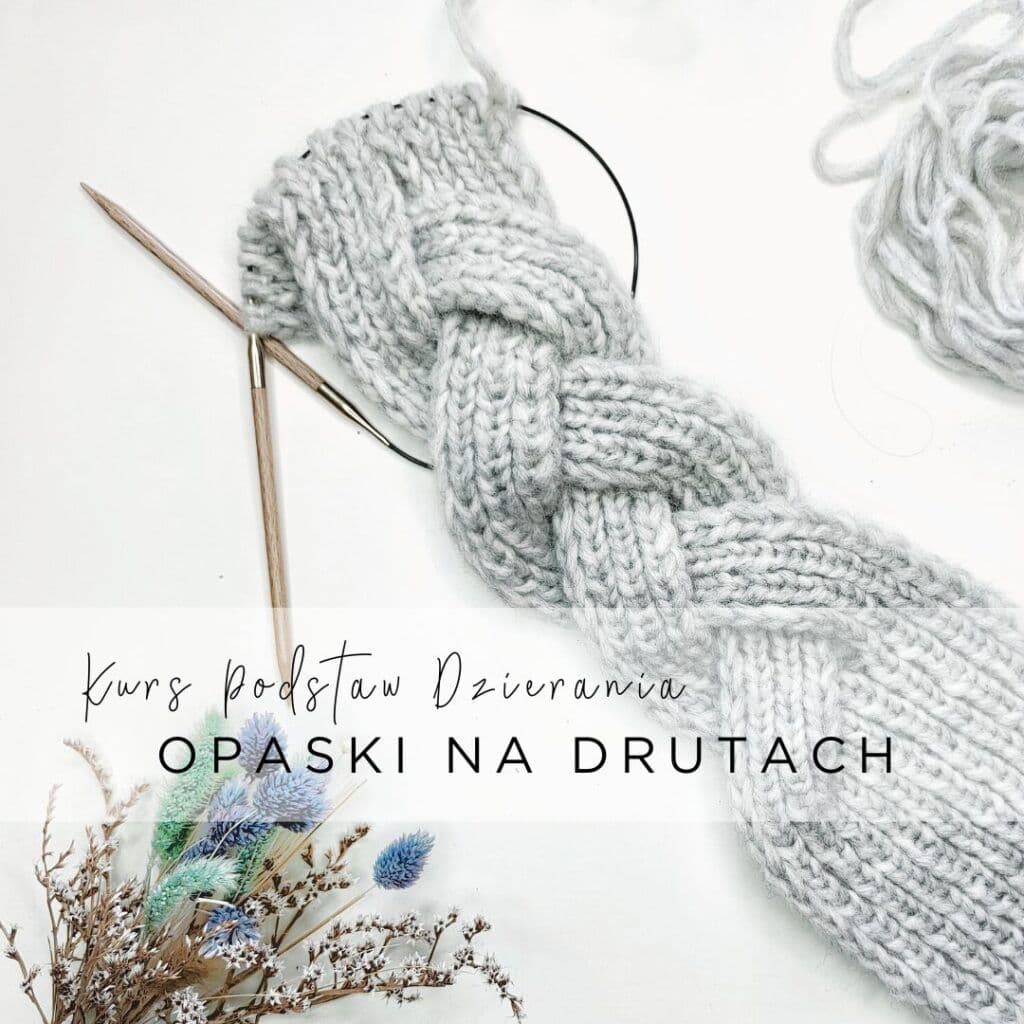 Na zdjęciu znajduje się robótka na drutach, prawdopodobnie szalik lub opaska, wykonana z grubej, szarej włóczki. Robótka ma wzór warkocza. Obok robótki znajdują się dwa drewniane druty połączone żyłką. W lewym dolnym rogu zdjęcia widoczny jest bukiet suszonych kwiatów w odcieniach niebieskiego, zielonego i brązowego.